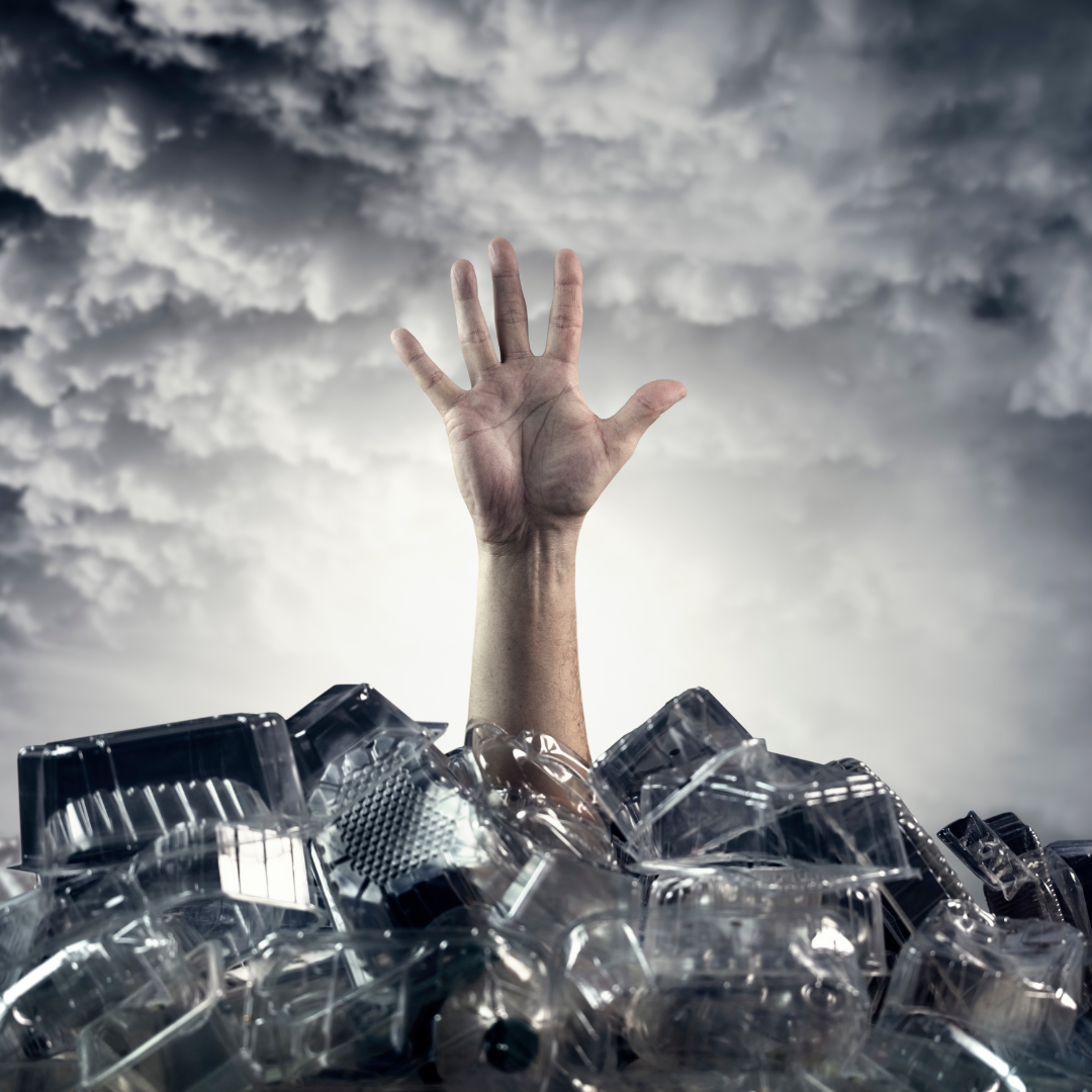 Hand reaching out of a pile of plastic waste symbolising the plastic pollution crisis in oceans.