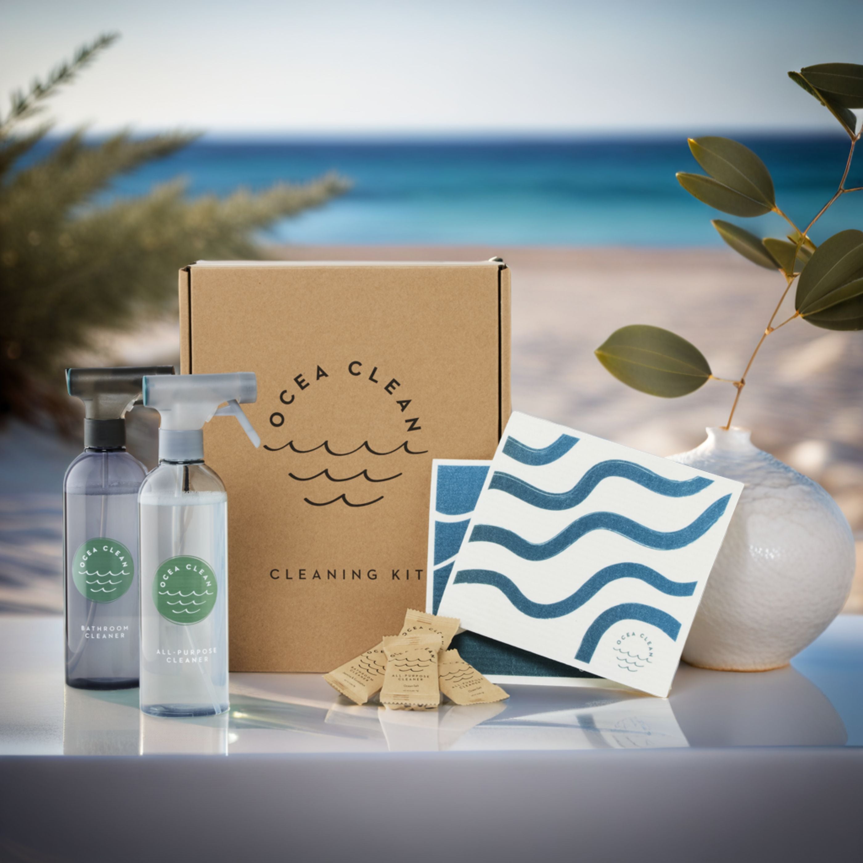 Ocea Clean cleaning kit with bottles, cloths, and box with ocean view.