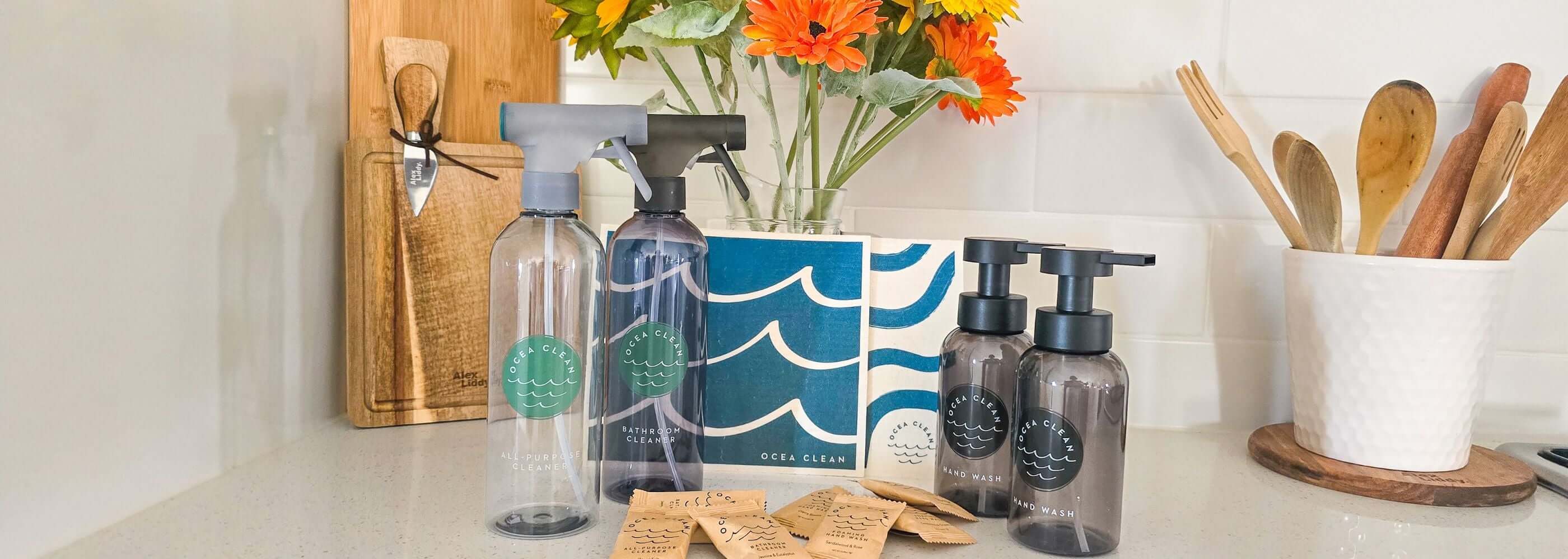 Kitchen counter with cleaning products, a vase of flowers, and wooden utensils.