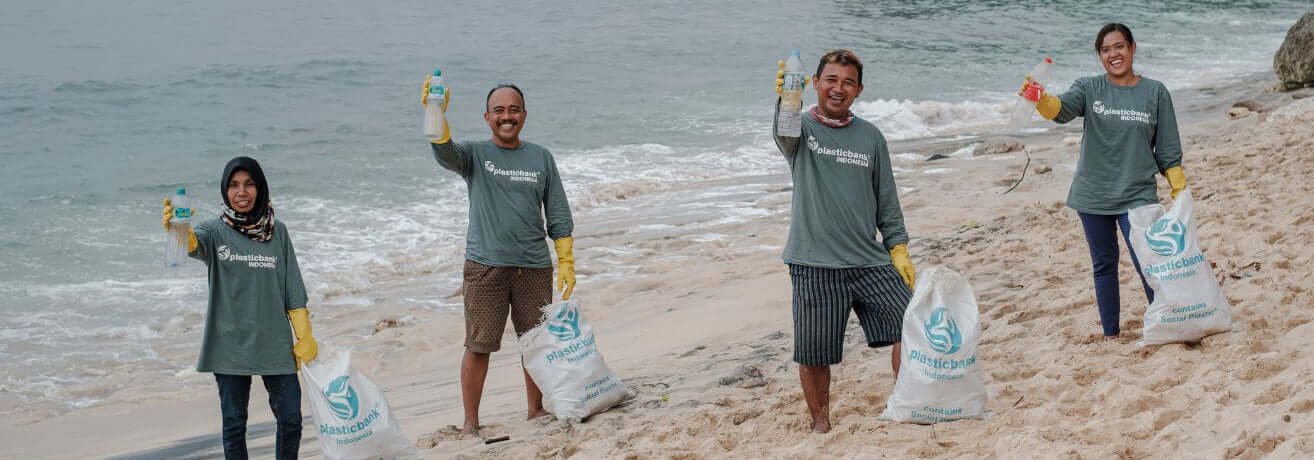 Group of people participating in a beach cleanup with bags and trash on a sandy beach.